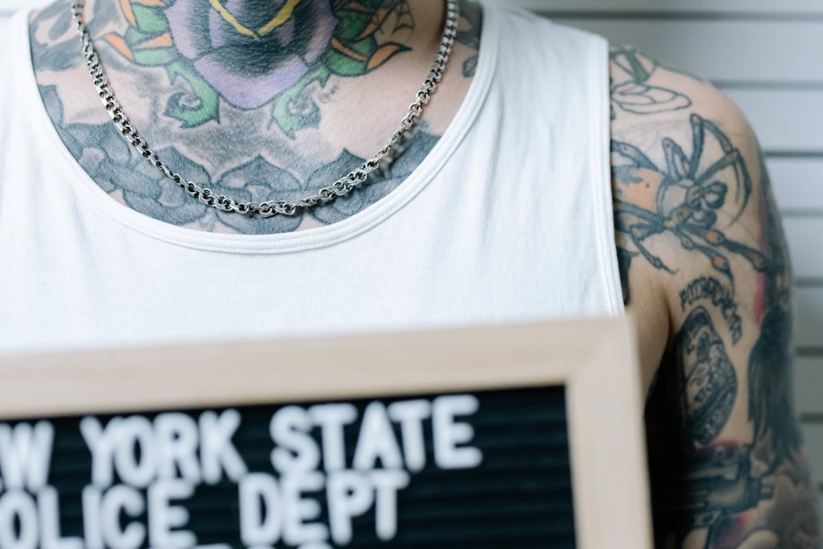 Close-up of a Tattooed Man Holding a Board on a Mugshot