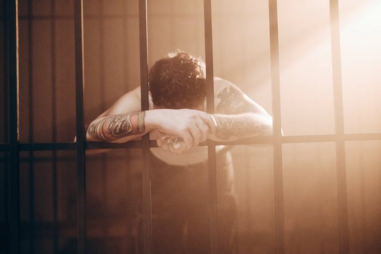 Man Leaning on Bars in Prison