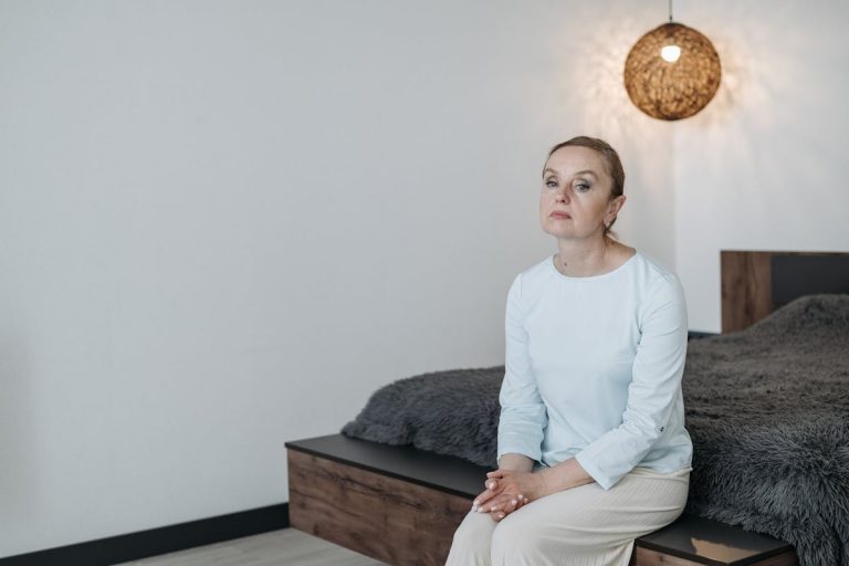 Woman Sadly Sitting on Edge of Bed