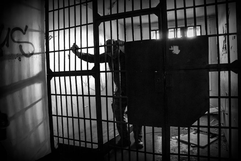 Grayscale Photo of a Prisoner Inside the Jail