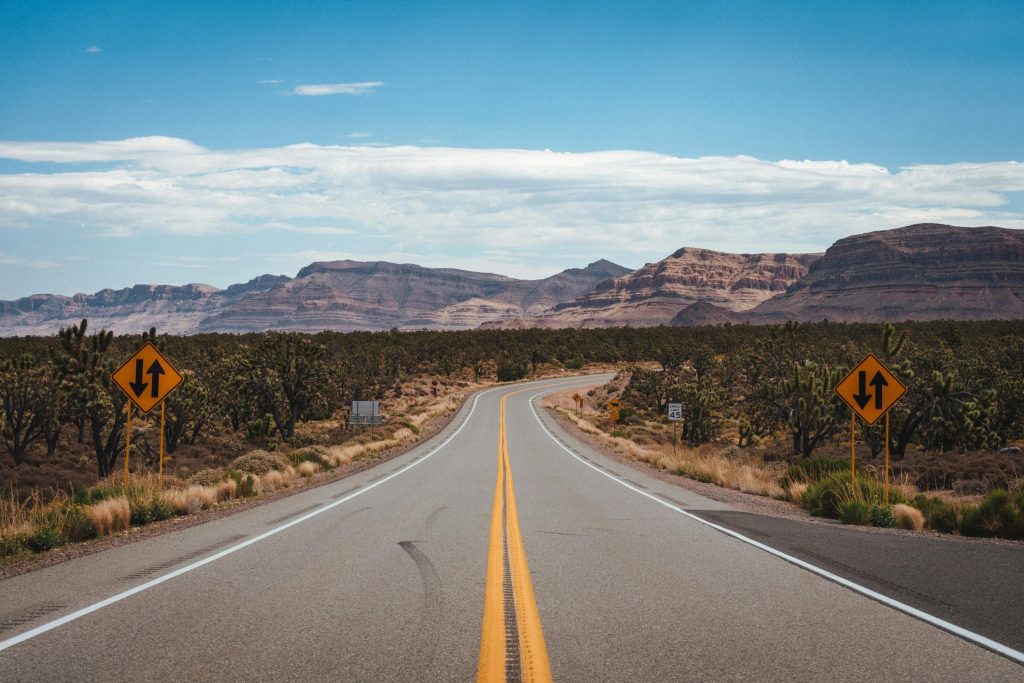 Asphalt road through cactus fields in mountainous valley in Arizona
